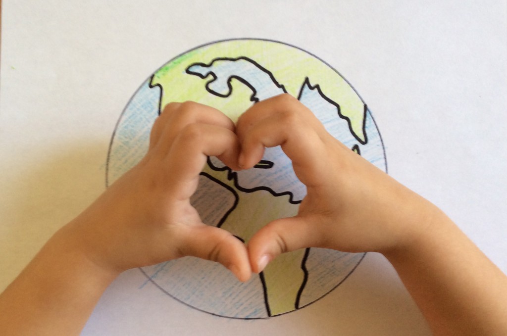 little hands making heart over earth drawing